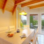 Esszimmer mit Holzdecke, Tisch mit Tischdecke und Blick auf Terrasse.