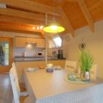 Essbereich mit Tisch und Stühlen, Küche im Hintergrund, Holzdecke und Fenster.