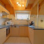 Küche mit Holzbalkendecke, Arbeitsplatten und Küchengeräten.