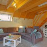 Wohnzimmer mit Sofa, Couchtisch und Holzdecke. Treppenhaus zur Unterkunft.