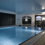 Innenpool mit Licht, Glasfronten und Außenterrasse