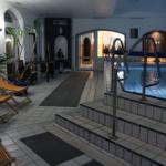 Innenpool mit Liegestühlen und Pflanzen. Treppen zum Einsteigen. Hintergrund mit Badebereich.