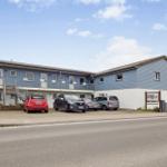 Apartmenthaus mit Balkonen und Parkplatz vorne.