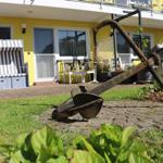 Vor dem Haus steht ein großer, rostiger Anker auf dem Rasen.