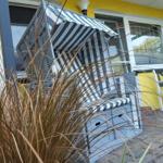 Strandkorb mit Streifen vor gelbem Haus und Pflanzen