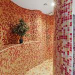 Duschbereich mit Mosaikfliesen, Pflanze und Waschbecken