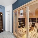 Sauna mit Holzliegen und Glaswand. Nebenher befindet sich eine weitere Sauna.