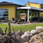 Gelbes Haus mit überdachtem Gartenbereich und Strandkorb.