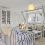 Wohnzimmer mit gestreiftem Sofa, Glaswand-Schrank und Fenster mit Blick.