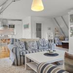 Wohn- und Küchenbereich mit Sofa, Esstisch und Glasvitrine.