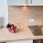 Küche mit Holzrückwand, Spüle und Obstschale