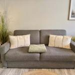 Ein grauer Sofa mit zwei Kissen und einer Decke.