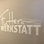 Wand mit Aufschrift Futter Werkstatt und Silhouetten von Gabel und Messer.