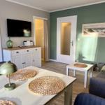 Wohn- und Essbereich mit Sofa, Tisch und Fernseher an der Wand.