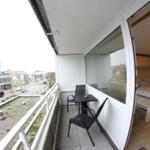 Balkon mit Tisch und Stühlen. Blick auf Straße und Gebäude.