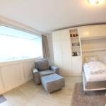 Zimmer mit zwei Betten, Sessel und Balkonzugang.