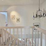Staircase with white railings and chandelier