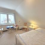Bedroom with sloped ceiling, bed, crib, table and chairs.