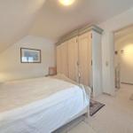 Bedroom with sloped ceiling, bed, wardrobe, and view into adjacent room.