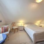 Bedroom with sloped ceiling, bed, nightstand, and chair.