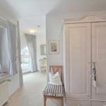 Bedroom with wardrobe, chair, and windows with curtains.