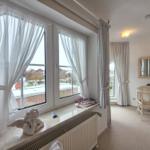 Room with large window, curtains, and desk with mirror.