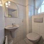 Bathroom with sink, mirror, toilet, and window.