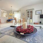 Living room with sofa, coffee table, and TV. Decor with red berries and candle.