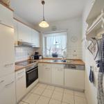 Kitchen with white cabinets, wooden countertop, and window with view outside.