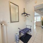 Entrance with mirror, bench, and coat rack. View into living room with sofa and plant.