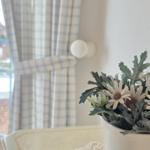 Flower arrangement on table in front of window with checkered curtains