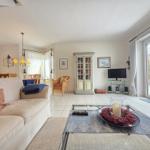 Living room with sofa, glass table, and TV. Passage to the kitchen.