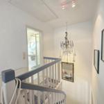 Staircase with mirror, chandelier, and view into bathroom.