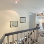 Staircase with pictures on the wall and view into living room.