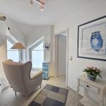 Entrance area with armchair, picture, and flowers on table