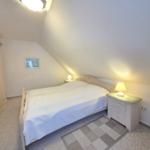 Bedroom with sloped ceiling, bed, nightstand, and wardrobe.