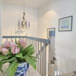 Staircase with flowers, railing, and wall pictures.