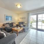 Living room with sofa, armchair, and glass door to the garden.