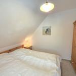 Bedroom with bed, wardrobe, and nightstand under sloped ceiling