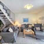 Living room with gray sofas, wooden table, and staircase to upper floor.