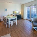 Wohn- und Essbereich mit Tisch, Stühlen, Sofa und Glasfront zur Terrasse.