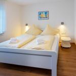 Schlafzimmer mit Doppelbett, Fenster und Wandlampen.