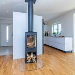 Moderne Küche mit Holzboden und Kaminofen im Zentrum.