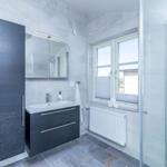 Badezimmer mit Dusche, Waschbecken und Fenster.