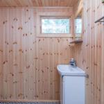 Holzbadezimmer mit Waschbecken, Toilette und kleinem Fenster.