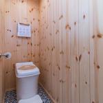 Bad mit Holzwänden, Toilette und Dusche.