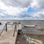 Holzsteg mit Bootssteg und kleinem Boot am Ufer.