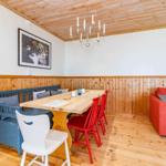 Essbereich mit Holztisch, roten Stühlen und blauer Bank. Wohnbereich mit rotem Sofa.