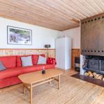Ein Wohnzimmer mit rotem Sofa, Holzdecke und Kamin mit Holz.