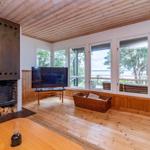 Wohnzimmer mit Kamin, Fernseher und Blick auf Wasser.
